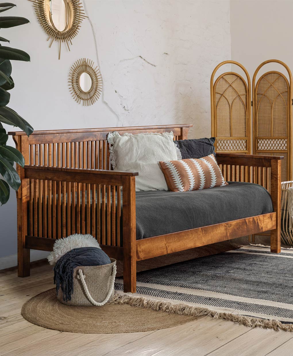 Wooden bed with wicker headboard in a room with decorative mirrors and plants.