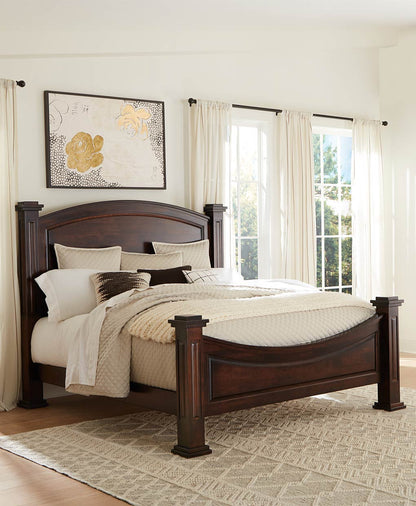 Wooden bed in a bedroom with white bedding and decorative pillows.