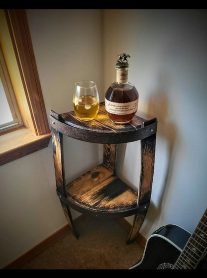 Bottle of whiskey and a glass on a wooden barrel table by a window.